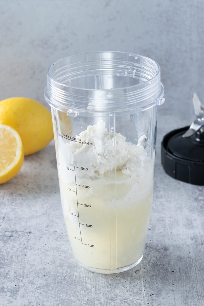 Scoops of vanilla ice cream added to concentrated lemon juice mixture in the blender.