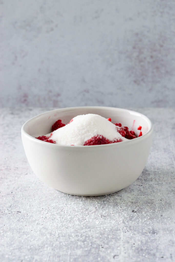 Bowl of raspberries with sugar on top.