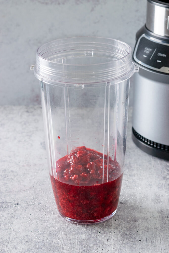 Raspberry and sugar mixture poured into a blender container.