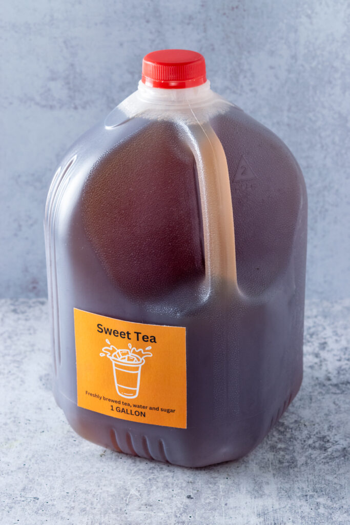 A gallon of sweet tea in a plastic jug that has a printable sweet tea, 1 gallon label on it.