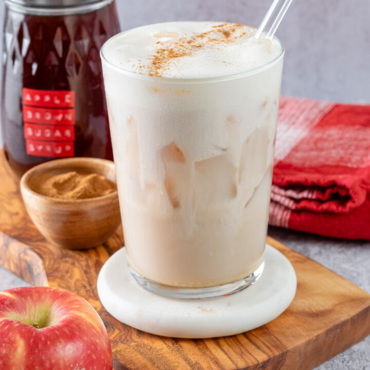 A Starbucks copycat Iced Apple Crisp Cream Chai Latte with a creamy layer of flavored cream on top with cinnamon sprinkled on.