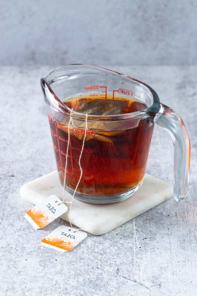 Brewing two chai tea bags in one cup of boiling water in a glass, heatproof measuring cup.