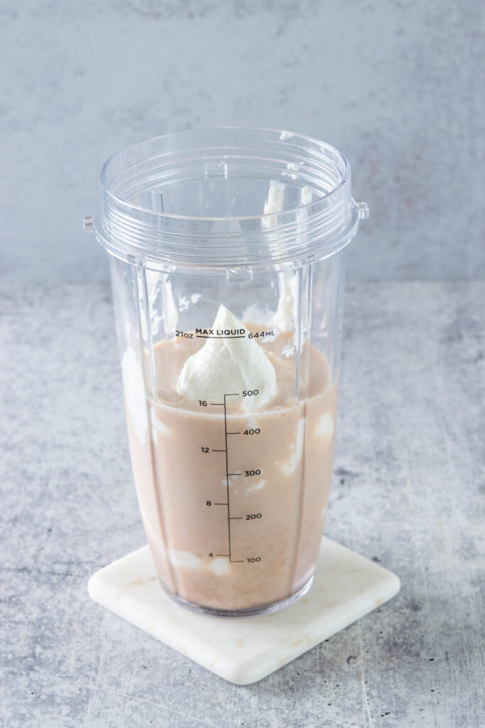 Greek yogurt added to a blender cup that already contains some milk and chai tea.