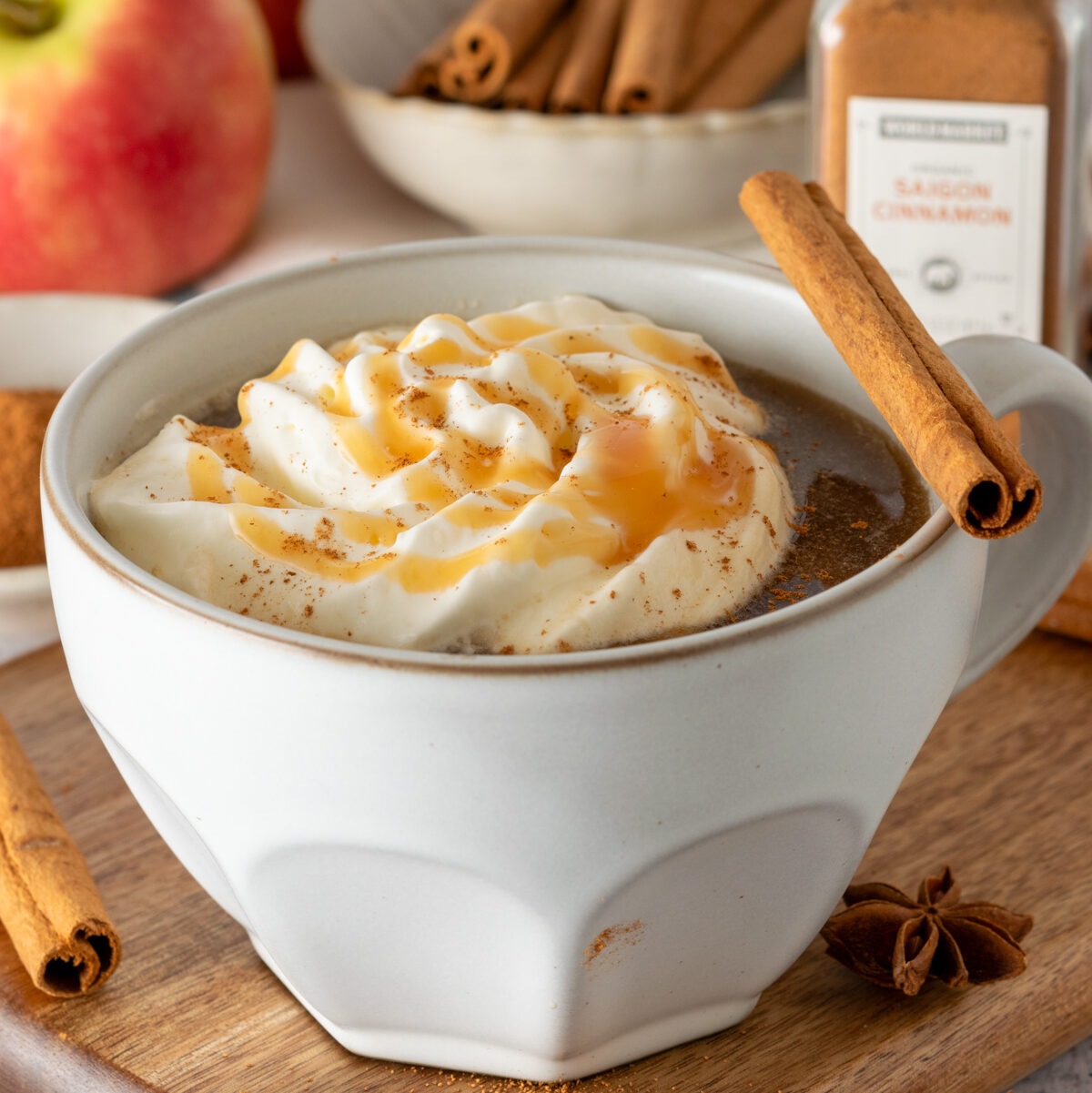 Navigation image for hot drink recipes, showing a hot apple cider chai, topped with whipped cream and cinnamon, in a mug