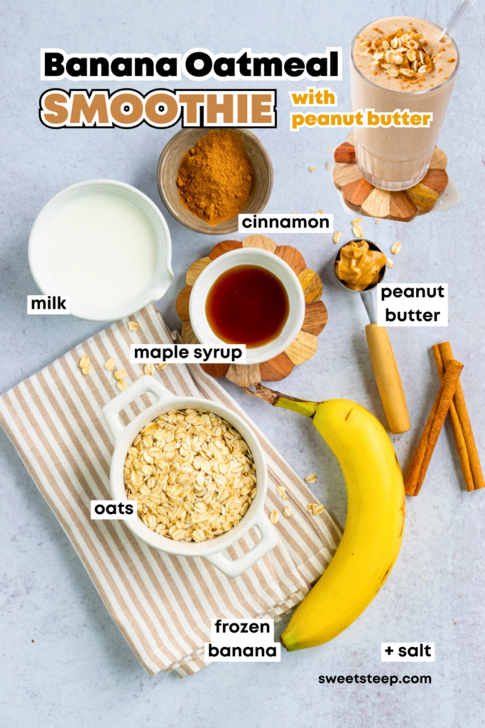 An overhead picture showing all the ingredients needed to make a homemade banana oatmeal smoothie with peanut butter. There's a bowl of oats sitting on a striped napkin, a bowl of cinnamon, a bowl of maple syrup, a tablespoon of peanut butter, some milk and a full banana.