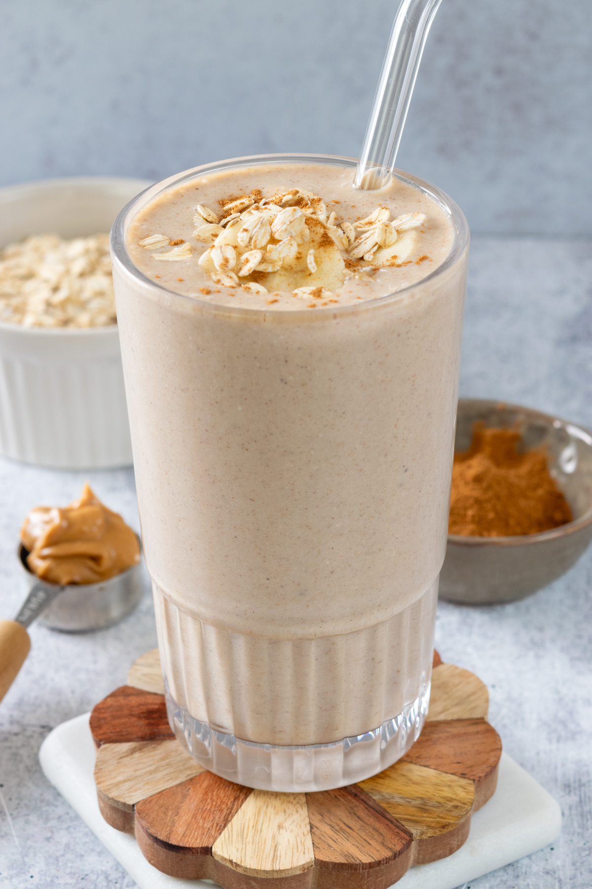 Homemade banana oatmeal smoothie with peanut butter, garnished with slices of bananas, oats and peanut butter drizzle.